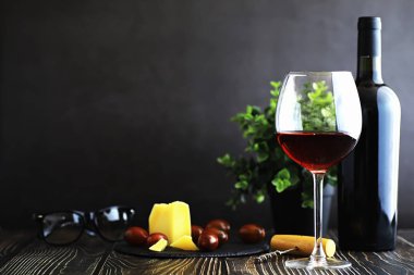 Masada bir bardak kırmızı kuru şarap. Siyah şişe ve bir bardak W