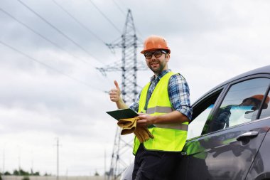 Kasklı ve üniformalı bir adam, sahada bir elektrikçi. Profesör.