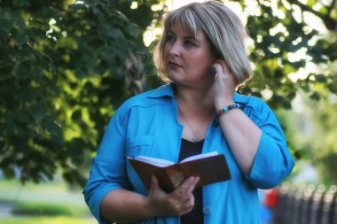 Parktaki kadın elinde kitapla yeşil ağaç 