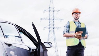 Kasklı ve üniformalı bir adam, sahada bir elektrikçi. Profesör.