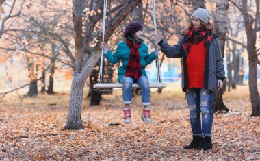 Kız sonbahar şehir parkında yaprak düşer. Genç güzel wi anne
