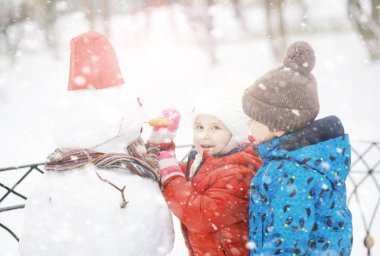 Kışın parktaki çocuklar. Çocuklar oyun oynarken karla oynuyor.
