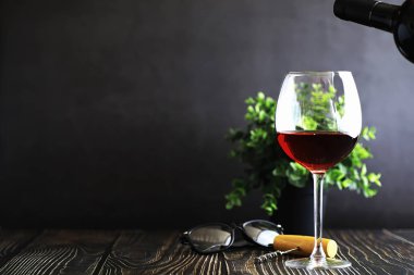 Masada bir bardak kırmızı kuru şarap. Siyah şişe ve bir bardak W