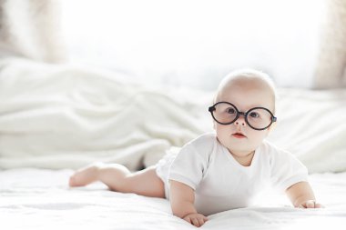 Yeni doğmuş bir bebek yumuşak bir yatakta gözlüklerle yatıyor..