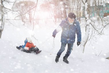 Kışın parktaki çocuklar. Çocuklar oyun oynarken karla oynuyor.