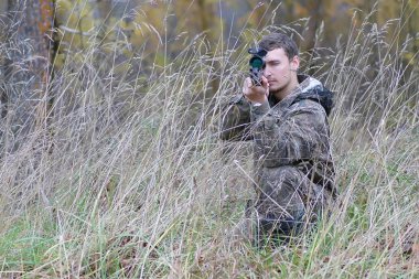Kamuflaj ve bahar hun üzerinde orman Kuşağı'nda silahlı adam