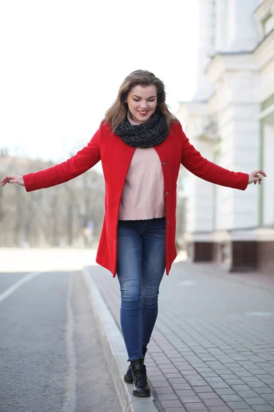 Красивая девушка на прогулке в красном пальто в городе — стоковое фото
