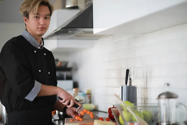 Cocinero asiático en la cocina prepara la comida en un traje de cocinero — Foto de Stock