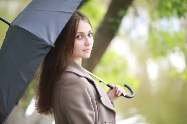 Chica joven en un abrigo en un parque de primavera —  Fotos de Stock