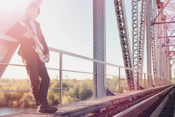 Um homem com uma guitarra eléctrica na estrada de ferro. Um músico em uma le — Fotografia de Stock