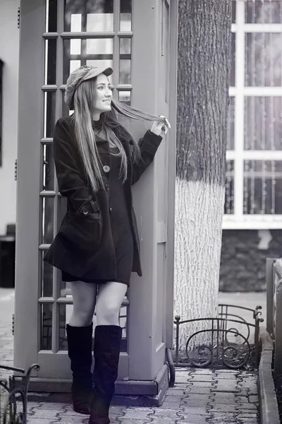 Bella ragazza in una cabina telefonica. La ragazza sta parlando. — Foto Stock