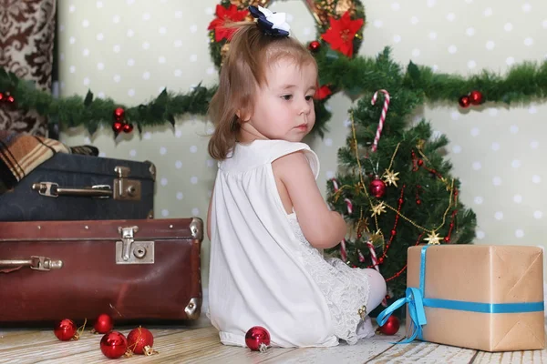 Menina sentada na frente de uma árvore de Natal — Fotografia de Stock