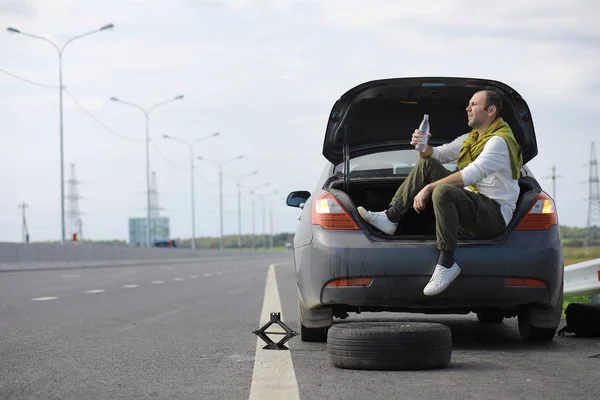 Sostituire la ruota di un'auto sulla strada. Un uomo che fa lavori di pneumatici — Foto Stock