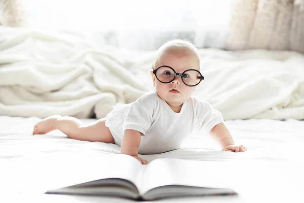 Egy újszülött egy puha ágyon fekszik szemüvegben.. — Stock Fotó