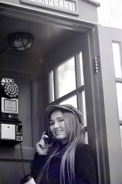 一个电话亭里漂亮的年轻女孩女孩在谈论 — 图库照片