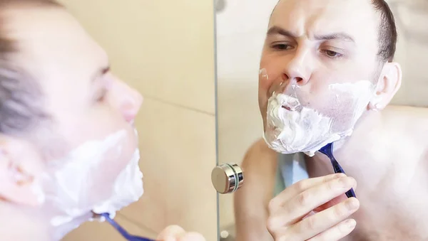 A man shaves in the bathroom in the morning — Stock Photo, Image