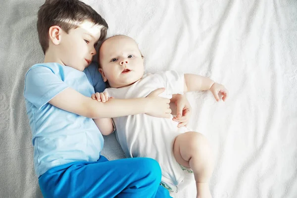 Діти лежать на ліжку поруч з новонародженою дитиною, маленька сестра . — стокове фото