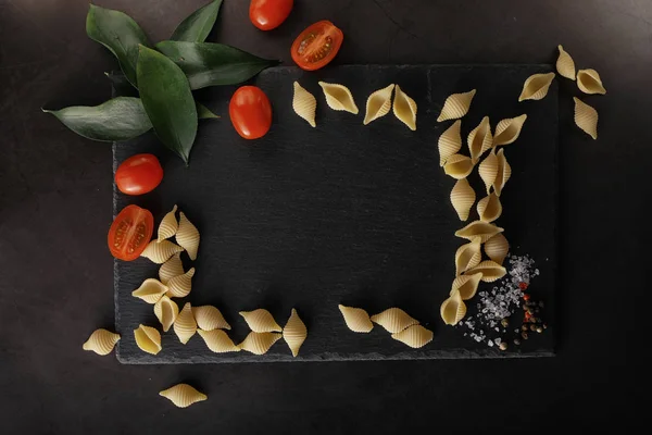 Nudelschalen auf schwarzem Stein. Tomaten und Lorbeerblätter mit Pallspi — Stockfoto