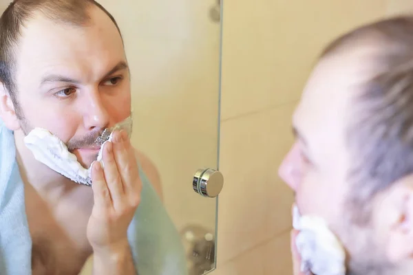 Um homem faz a barba na casa de banho pela manhã — Fotografia de Stock