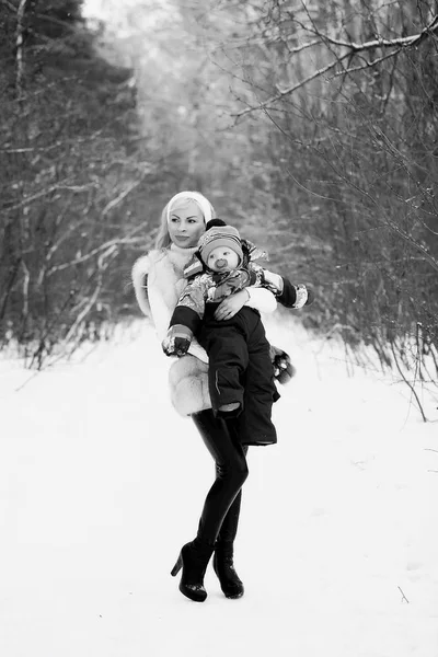 En ung mamma går på en vinterdag med en baby i famnen — Stockfoto