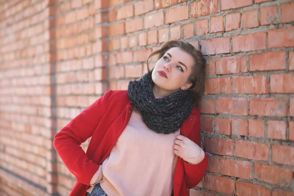 Jolie fille en manteau rouge sur le mur de briques — Photo