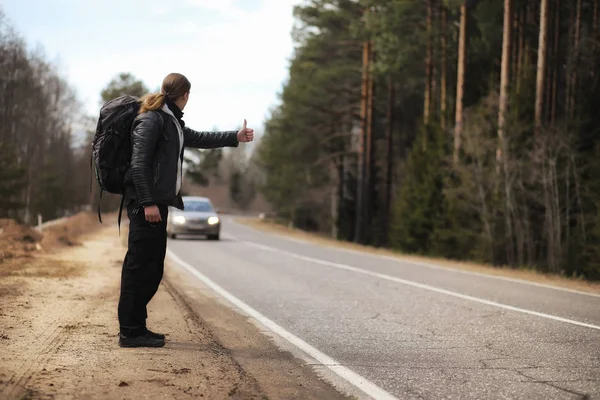 A young man is hitchhiking around the country. The man is trying — Stock Photo, Image