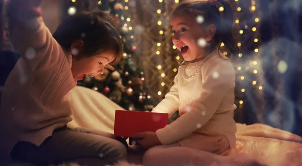 Familie an Heiligabend am Kamin. Kinder öffnen Weihnachtsgeschenke — Stockfoto