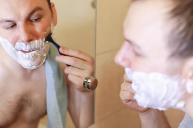 Bir adam sabahları banyoda tıraş oluyor.