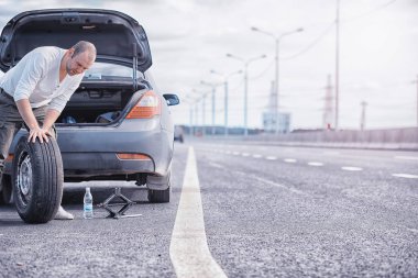 Yoldaki bir arabanın tekerleğini değiştirmek. Lastik işi yapan bir adam. 
