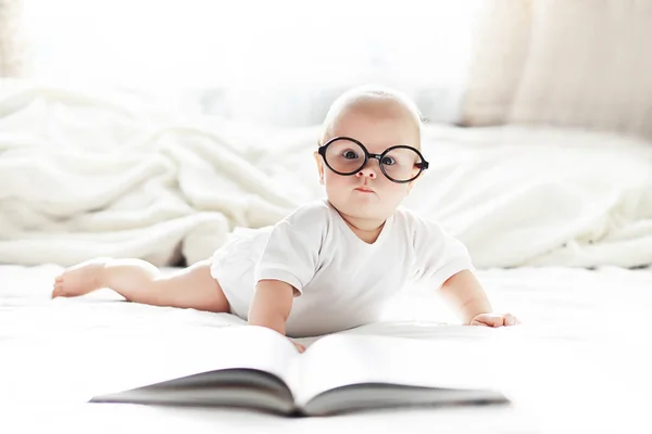 Een pasgeboren baby ligt op een zacht bed in een bril. — Stockfoto