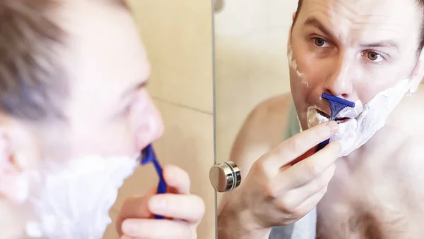 Um homem faz a barba na casa de banho pela manhã — Fotografia de Stock