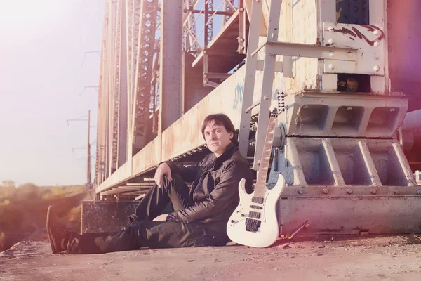 Un hombre con una guitarra eléctrica en el ferrocarril. Un músico en una le — Foto de Stock