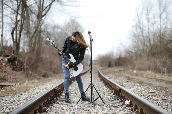 Una chica músico de rock en una chaqueta de cuero con una guitarra — Foto de Stock