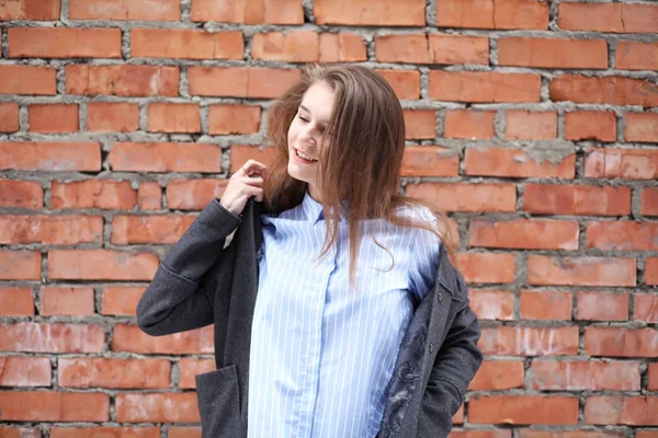 stock image Young beautiful girl near red brick wall posing