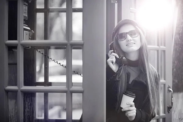 Menina bonita em uma cabine telefônica. A menina está falando no th — Fotografia de Stock