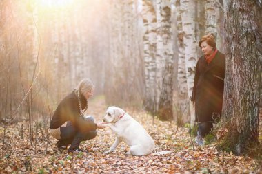 Sonbahar bahçesinde annesiyle köpek gezintisine çıkmış genç bir kız.
