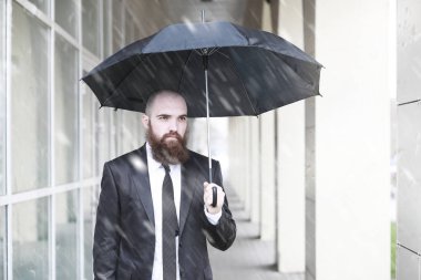 Takım elbiseli kel sakallı bir adam.