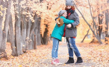 Kız sonbahar şehir parkında yaprak düşer. Genç güzel wi anne