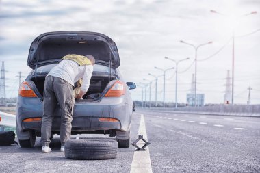 Yoldaki bir arabanın tekerleğini değiştirmek. Lastik işi yapan bir adam. 
