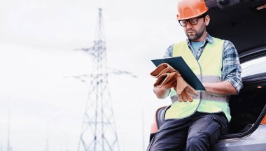 Kasklı ve üniformalı bir adam, sahada bir elektrikçi. Profesör.