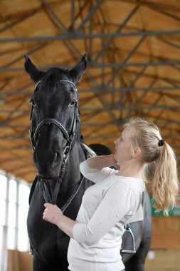 İnsanlar ahşap bir arenada at eğitiminde.