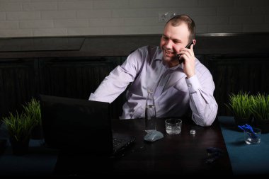 Masada oturan ve dizüstü bilgisayarda çalışan adam