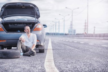 Yoldaki bir arabanın tekerleğini değiştirmek. Lastik işi yapan bir adam. 