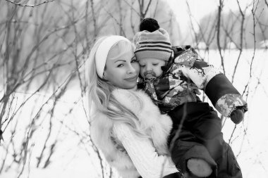 Genç bir anne kucağında bir bebekle bir kış gününde yürür