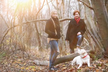 Sonbahar bahçesinde annesiyle köpek gezintisine çıkmış genç bir kız.