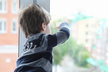 Küçük çocuk bir kitap okuyor. Çocuğun pencerenin önünde oturur bir