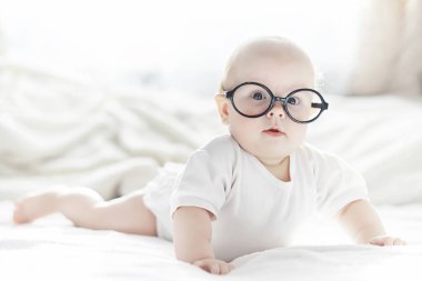 Yeni doğmuş bir bebek yumuşak bir yatakta gözlüklerle yatıyor..