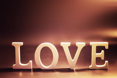 Tahta ve metal harfler koyu siyah üzerine yazılmış aşk kelimelerini oluşturur.