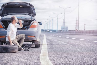 Yoldaki bir arabanın tekerleğini değiştirmek. Lastik işi yapan bir adam. 