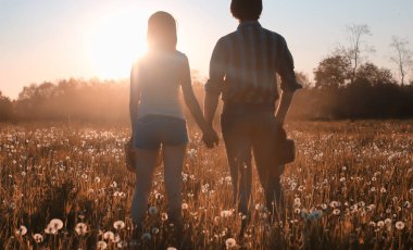 Bir çift genç adam ve bir kız sonbahar parkında yürüyorlar.